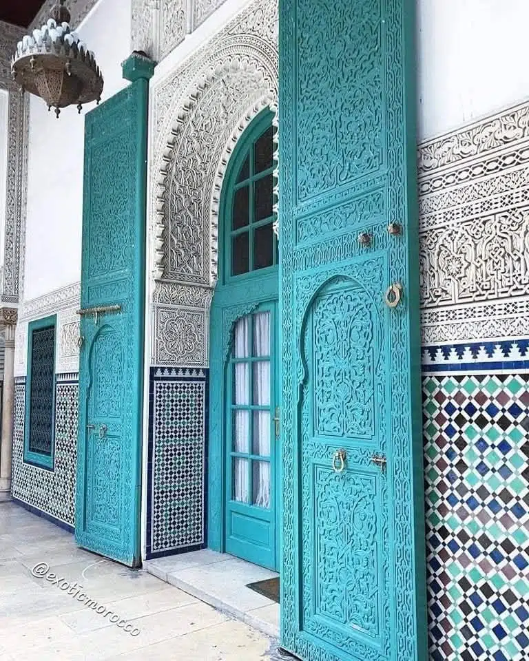 Carved turquoise Moroccan doors with zellige walls