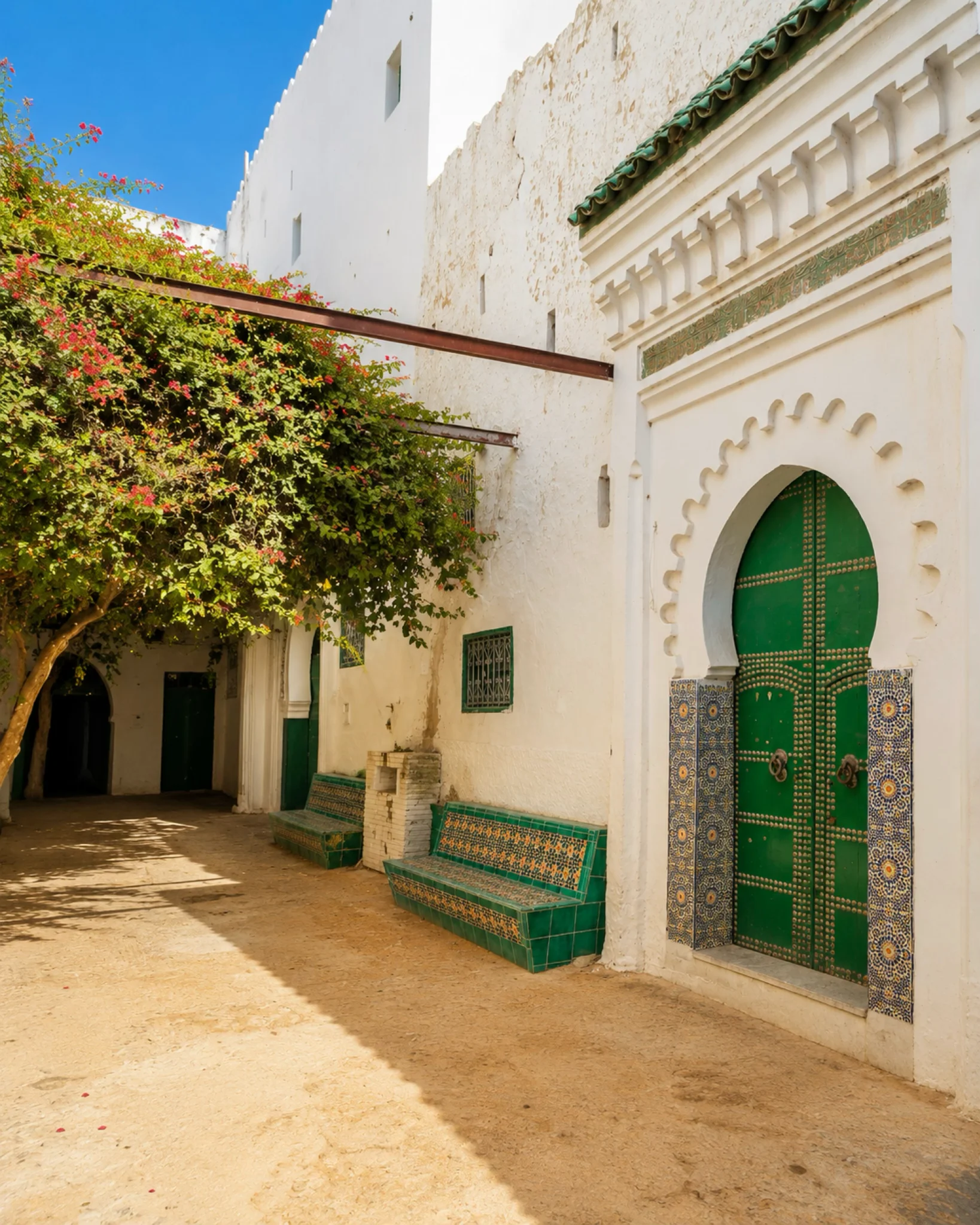 Green door, zellige benches and shaded courtyard in Tétouan